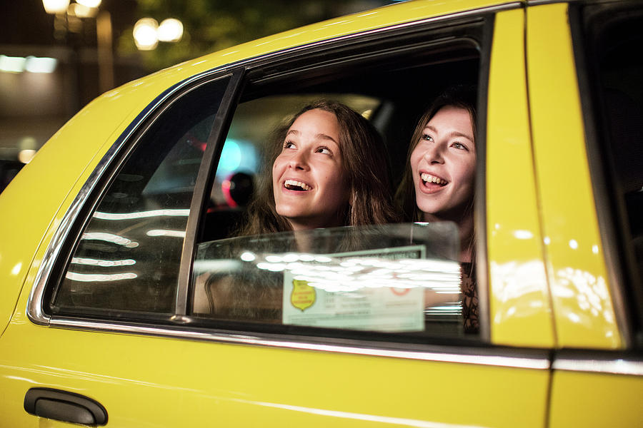 Smiling Female Friends Looking Through Window While Traveling In Taxi