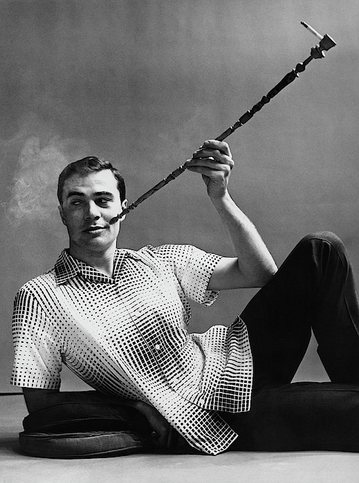 Emme Gene Hall - A Male Model Smoking A Cigarette From A Long Pipe