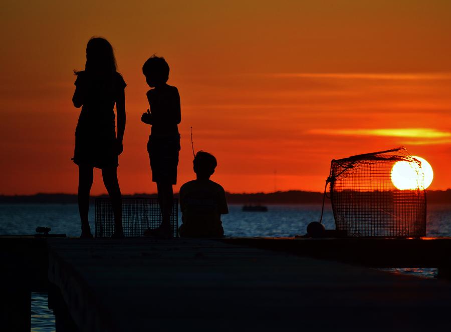 Perfect Ending - 3 friends on a pier as the hot summer sun sets on the Indian River Bay Photograph by Billy Beck