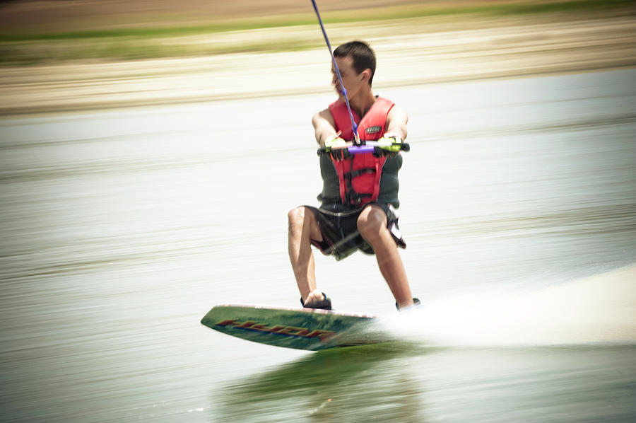 A Teenage Boy Skims Across Water Photograph by Kevin Steele - Pixels