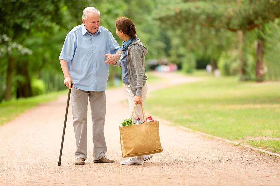 Caregiver – woman helping senior man with shopping #1 Photograph by FredFroese