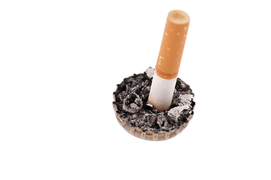 Cigarette butt and ash in a bottle cap #1 Photograph by Marek Poplawski