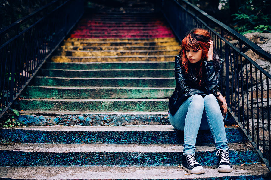 Depressed teenager sitting lonely outdoors #1 Photograph by Pixelfit