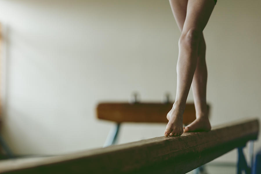 Female gymnast walking on balance beam, low section Photograph by Vgajic