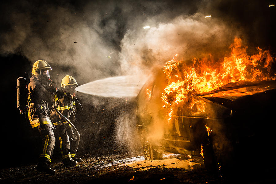 Firefighters spraying water on burning car #1 Photograph by Simonkr