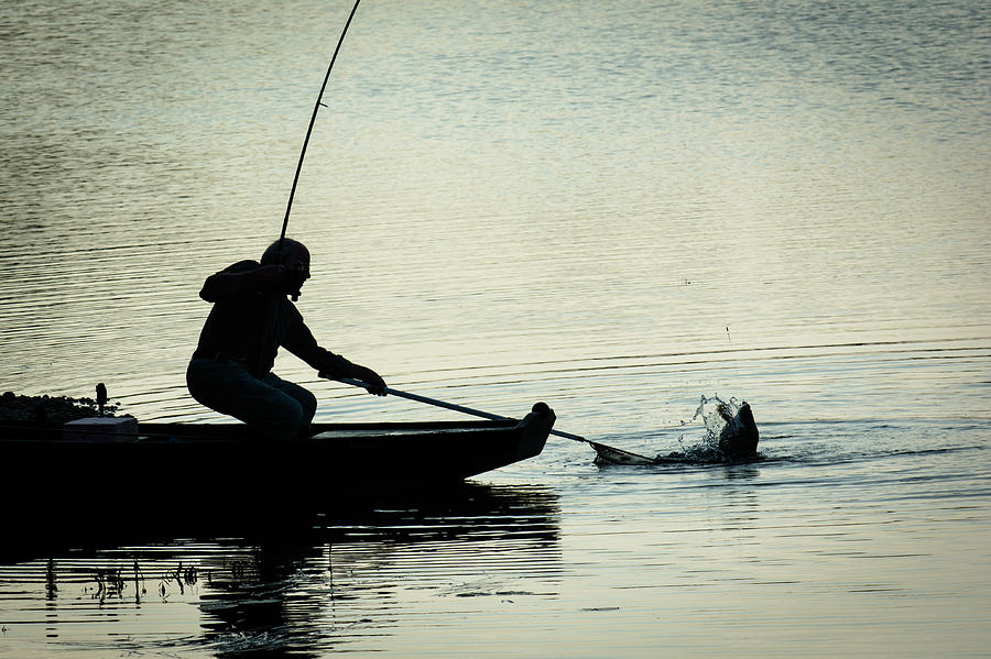 Fisherman Catching Fish On A Twilight Lake Photograph by Andreas Berthold