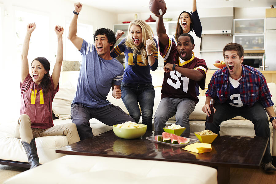Friends watching football in living room. #1 Photograph by Robert Deutschman