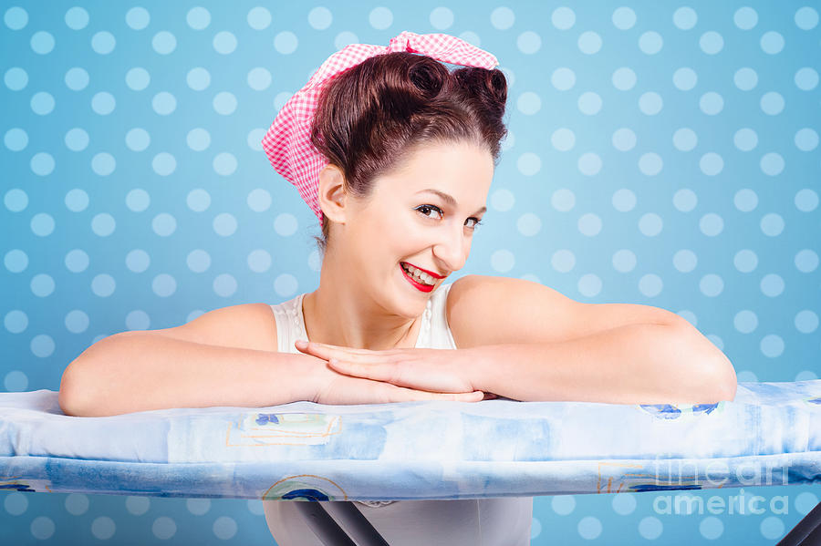 Portrait Photograph - Happy 60s pinup housewife on blue ironing board #1 by Jorgo Photography