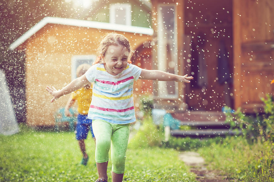 Happy little girl and boy playing with garden sprinkler #1 Photograph by ArtMarie