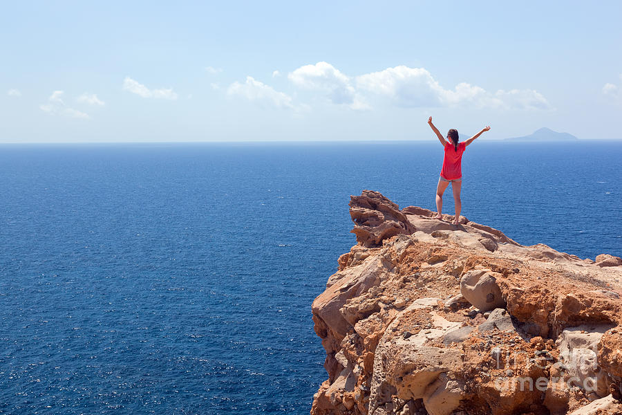 Greek Photograph - Happy woman on the rock with hands up #1 by Michal Bednarek