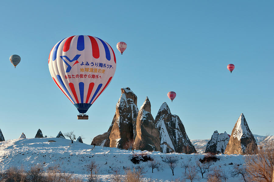 Hot Air Balloons Over Snow Covered Rock #1 Photograph by Izzet Keribar