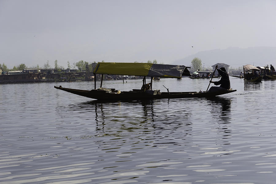 Kashmiri man rowing a shikara without tourists in the waters of the Dal Lake #1 Photograph by Ashish Agarwal