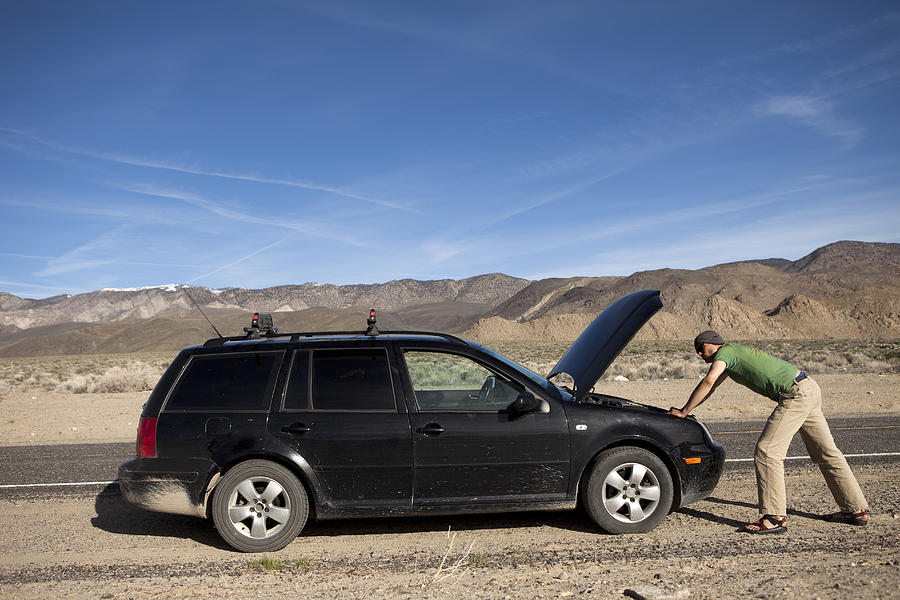 Man standing near a broke down car. #1 Photograph by Jordan Siemens