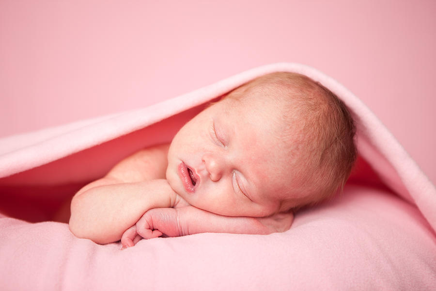 Newborn Baby Girl Sleeping Peacefully Under a Pink Blanket #1 Photograph by Ideabug