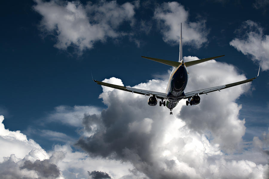 Transportation Photograph - Passenger jet landing against a blue sky with white fluffy cloud #1 by Ken Biggs