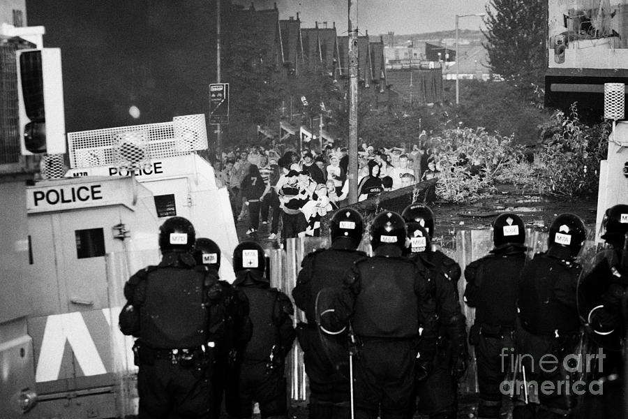 Northern Photograph - PSNI riot officers face rioters mob on crumlin road at ardoyne shops belfast 12th July #1 by Joe Fox