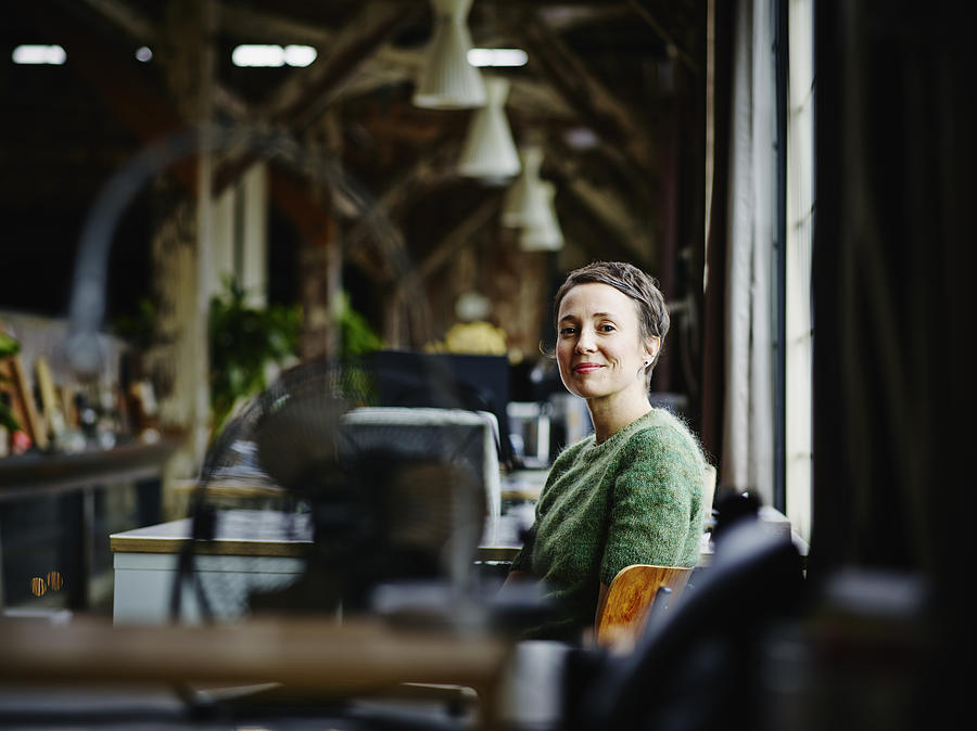 Smiling businesswoman sitting at workstation Photograph by Thomas Barwick