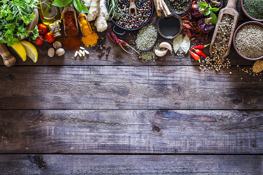 Spices and herbs border on rustic wood kitchen table #1 Photograph by Fcafotodigital