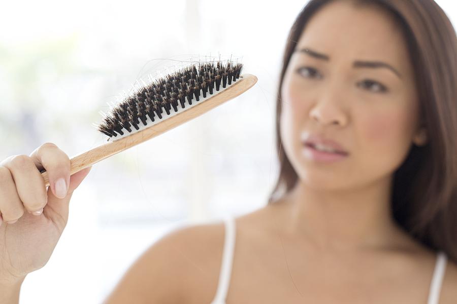 Woman holding hairbrush with worried expression #1 Photograph by Science Photo Library