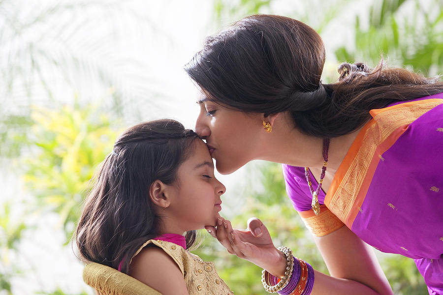 Woman kissing her daughters forehead #1 Photograph by Hemant Mehta