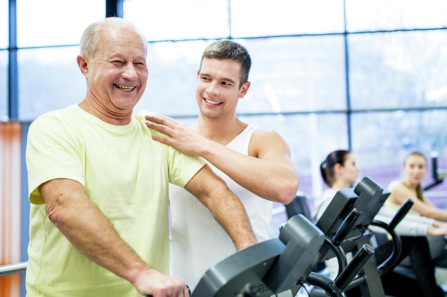 Young Man Assisting Senior Man In Gym #1 Photograph by Science Photo Library