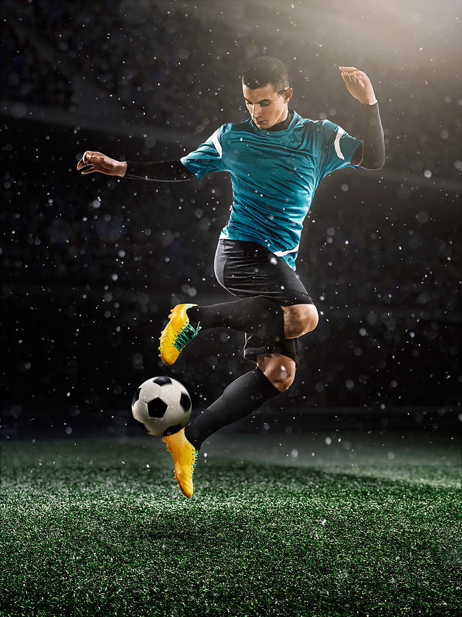 Soccer player kicking ball in stadium #14 Photograph by Dmytro Aksonov