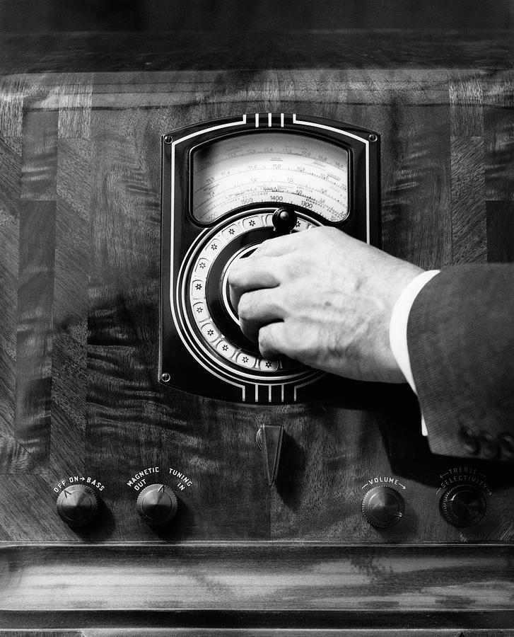 Black And White Photograph - 1930s Close Up Mans Hand Turning Radio by Vintage Images