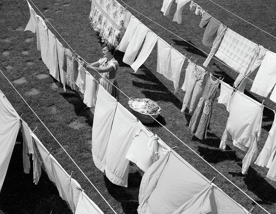 Black And White Photograph - 1950s Housewife Hanging Laundry by Vintage Images