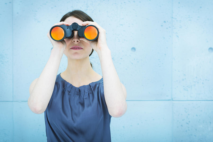 Businesswoman holding binoculars Photograph by Caracterdesign