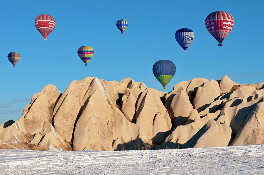 Hot Air Balloons Over Snow Covered Rock #2 Photograph by Izzet Keribar