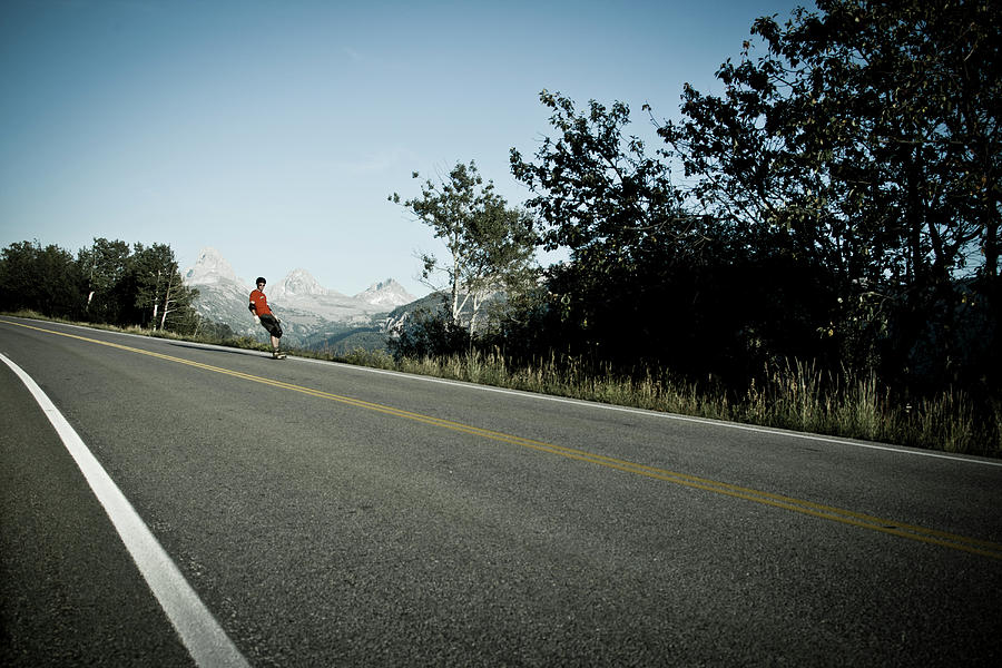 Landscape Photograph - Male Rides Long Board Down Paved Road #2 by Gabe Rogel