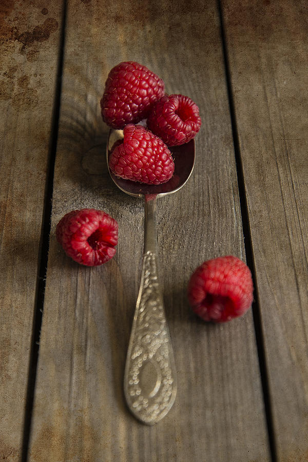 Raspberries in rustic kitchen setting with wooden background wit
