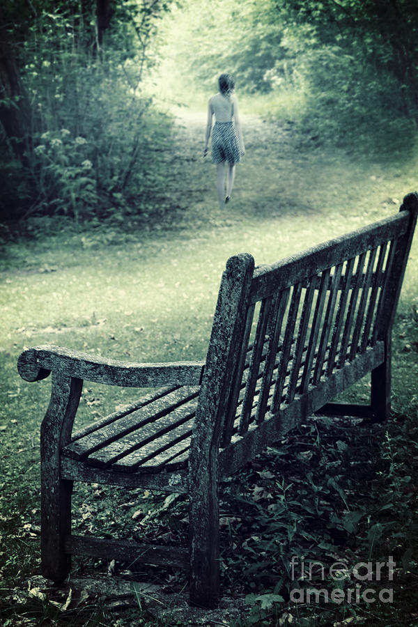 Wooden bench in a park with woman walking away #2 Photograph by Sandra Cunningham