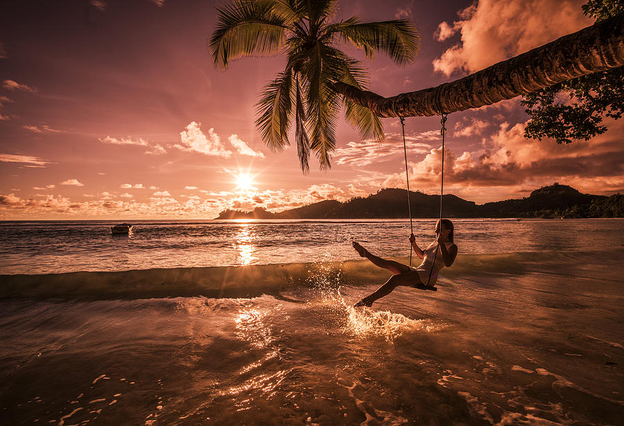 Carefree woman swinging above the sea at sunset beach. #3 Photograph by BraunS