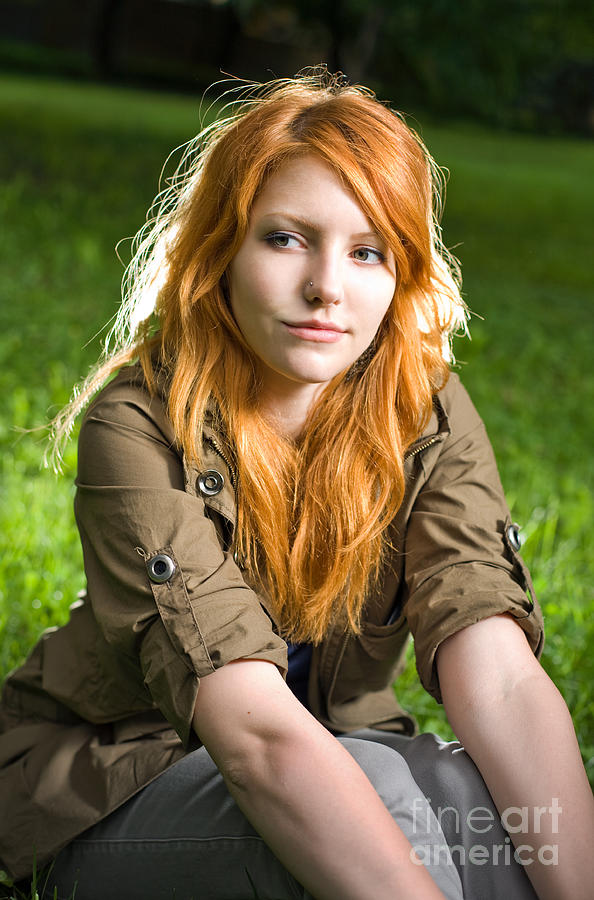 Romantic Portrait Of A Young Redhead Girl Sitting In The Park