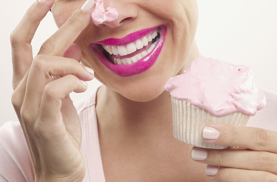 Woman with pink lipstick and frosting on nose eating cupcake #3 Photograph by Chris Ryan