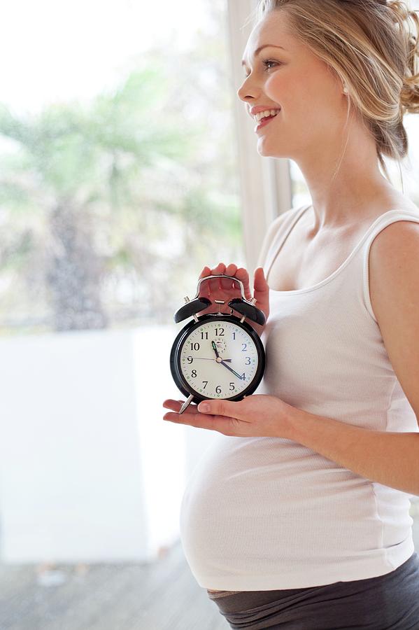 Pregnant Woman Holding Alarm Clock Photograph by Ian Hooton/science ...
