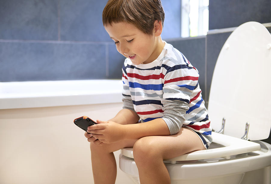 5 Year Old Playing On Phone In The Toilet Photograph by Peter Dazeley