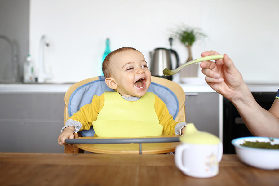 A 1 year old baby boy eating in his high chair Photograph by Catherine Delahaye