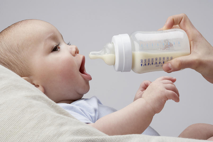 A baby being fed a bottle Photograph by OJO Images