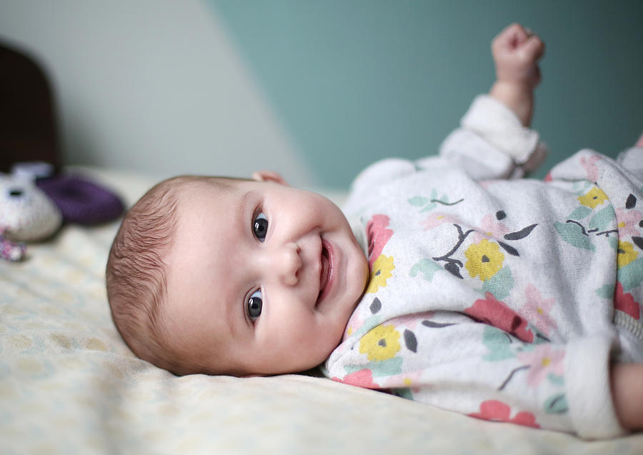 A baby girl smiling on a bed Photograph by Catherine Delahaye