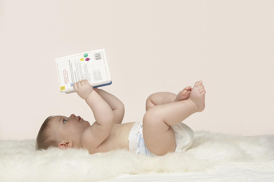 A baby looking at a book Photograph by OJO Images