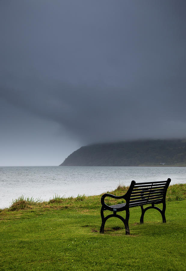A Bench At The Waters Edge With A Dark Photograph by John Short / Design Pics