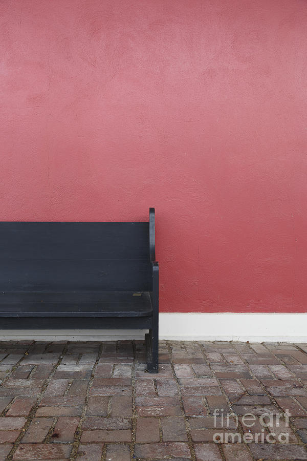 A bench in front of a red stucco wall Photograph by Edward Fielding