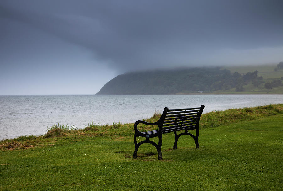 A Bench Sits On The Waters Edge With Photograph by John Short / Design Pics
