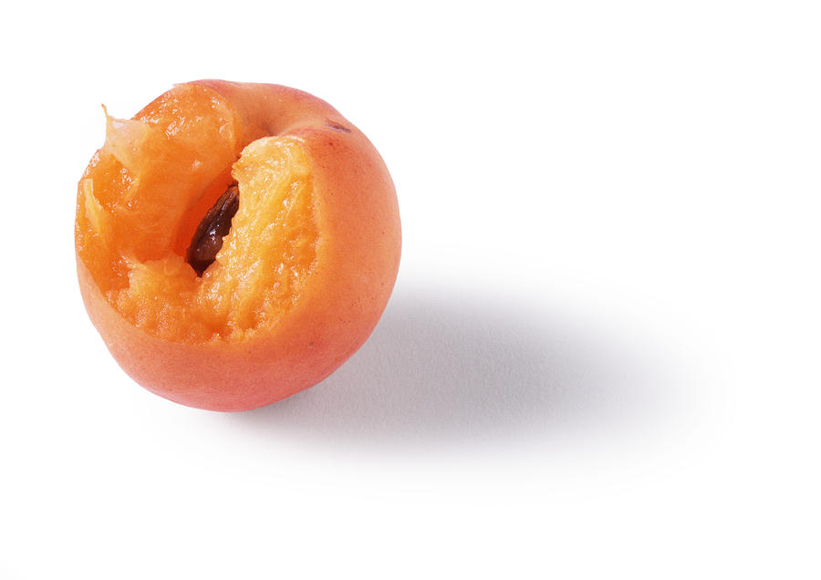 A bitten apricot, white background Photograph by Isabelle Rozenbaum