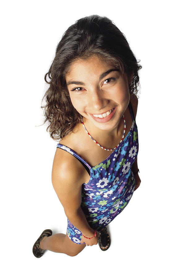 A Brunette Hispanic Teenage Girl Wearing Black Sandals And A Flower Dress With Spaghetti Straps And Necklace Smiles As She Looks Up Toward The Camera Photograph by Photodisc
