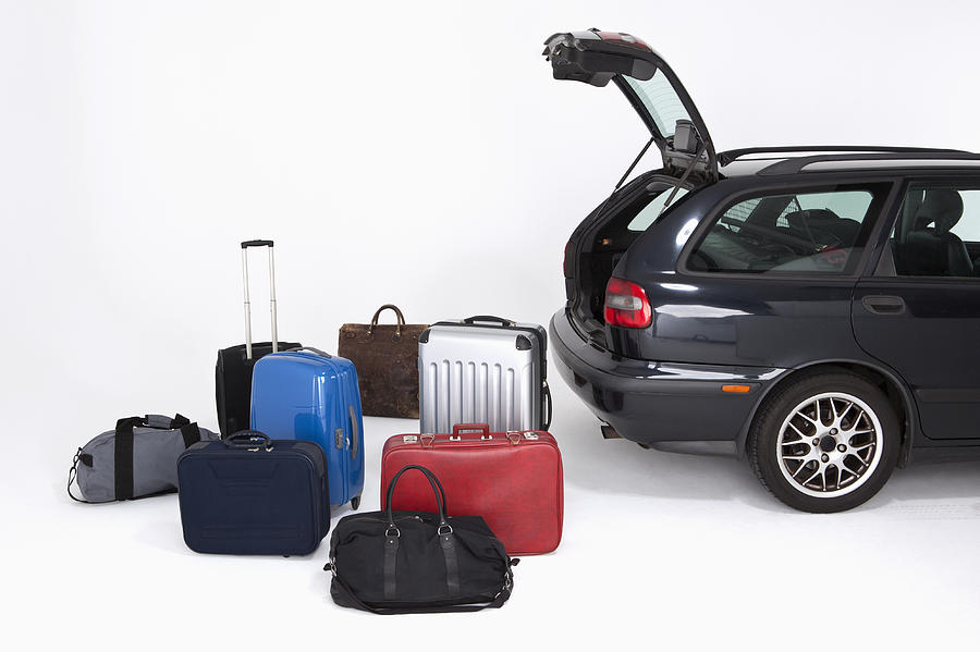 A bunch of different pieces of luggage next to an open car trunk Photograph by Halfdark