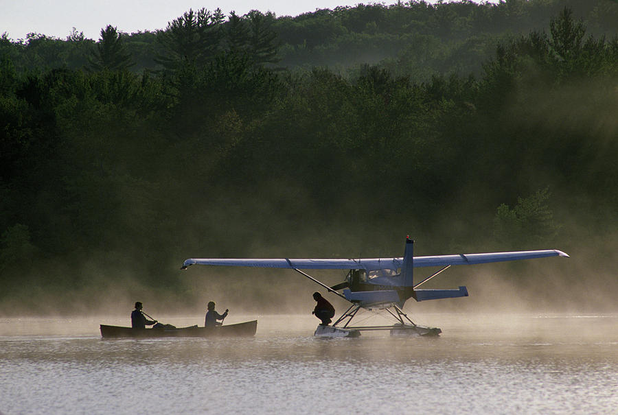A Canoe Paddles To A Float Plane Photograph by Jose Azel