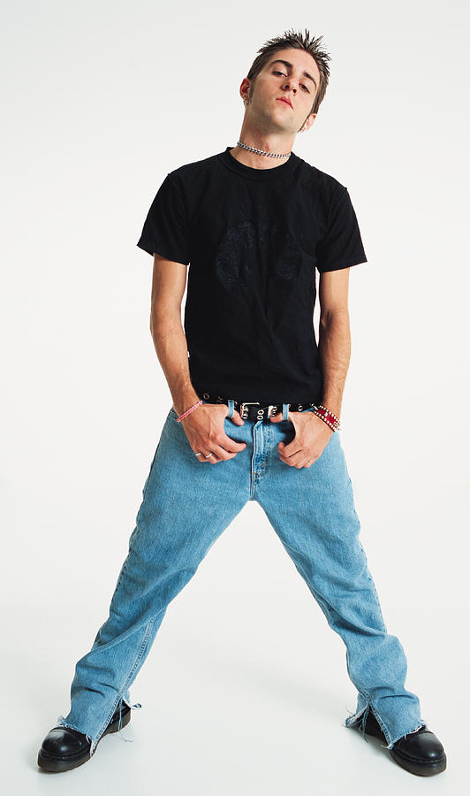 A Caucasian Teenage Boy With Spiked Brown Hair Is Wearing Jeans And A Black Teeshirt As He Stands With Legs Apart And Thumbs Hanging From Belt Loops And Looks Impassively At The Camera Photograph by Photodisc